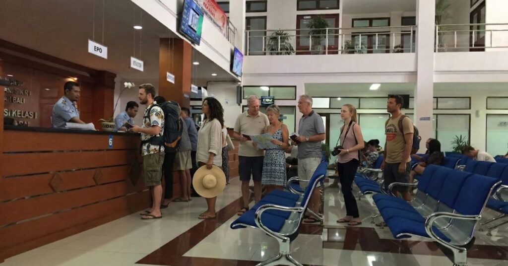 Foreign travelers lining up at an indonesian immigration office counter to submit supporting documents for an emergency stay permit (itkt).