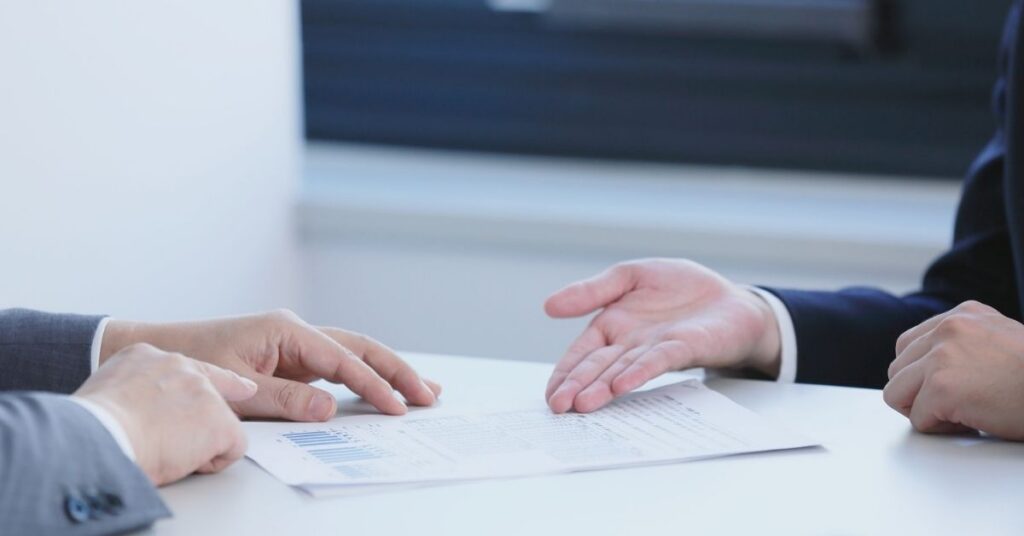 Due persone in riunione che esaminano e gesticolano su documenti, in rappresentanza della richiesta di un visto di preinvestimento per l'Indonesia.