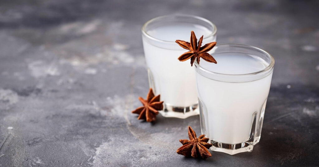 Two small glasses of milky arak with star anise, representing local alcohol in indonesia and the importance of avoiding methanol poisoning.