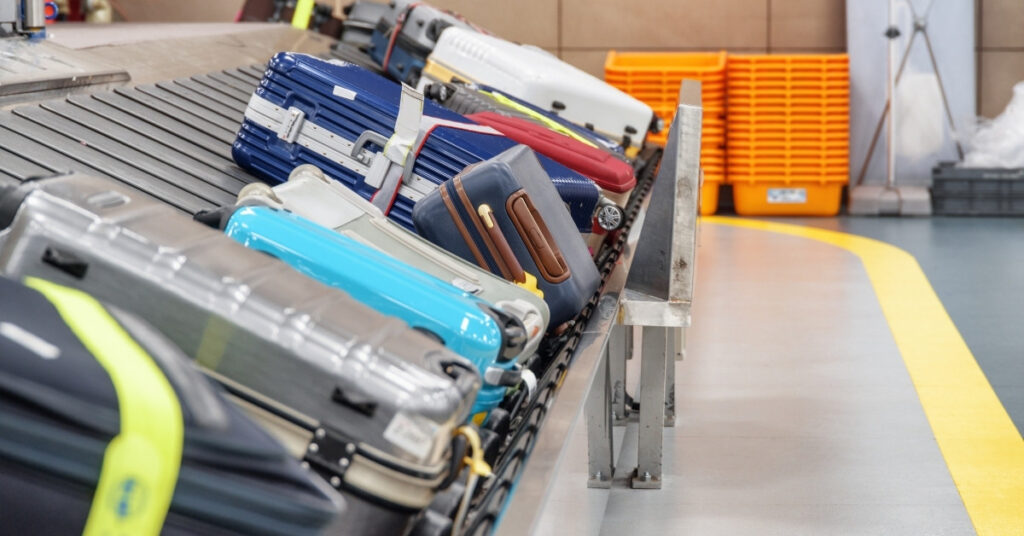 Suitcases circling a baggage carousel at Bali’s Ngurah Rai Airport. Passengers collecting checked bags for self-transfer or customs during a layover.