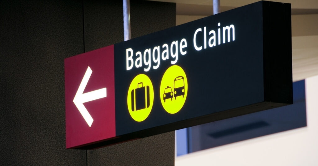 Illuminated baggage claim sign inside Bali Airport terminal.