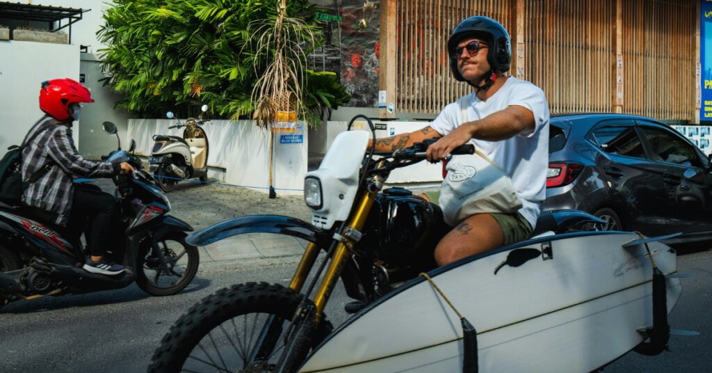 Man rijdt op een motor met surfplankrek in canggu-achtig verkeer, gebruikelijk bali-vervoer voor nomaden en surfers.