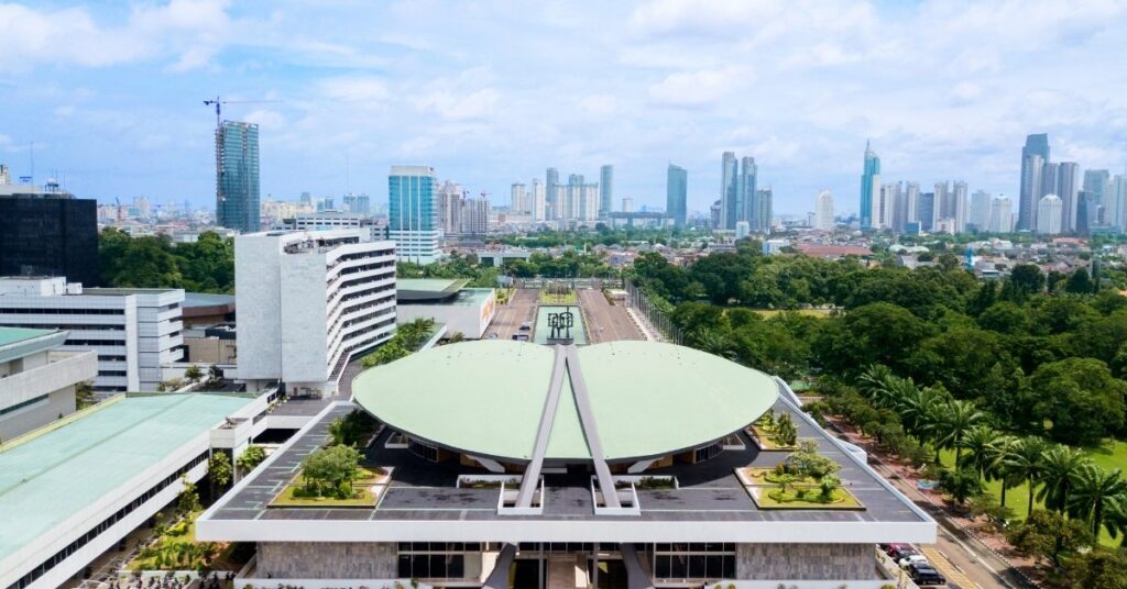 Widok z lotu ptaka na duży budynek rządowy z zieloną kopułą, przedstawiający dyskusje polityczne stojące za propozycją wejścia Bali do 2026 roku.