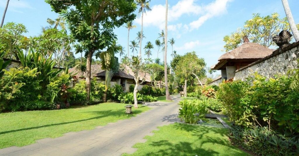Lush villa lane in Jimbaran with tropical gardens and thatched roofs, quiet, upscale living for retirees.