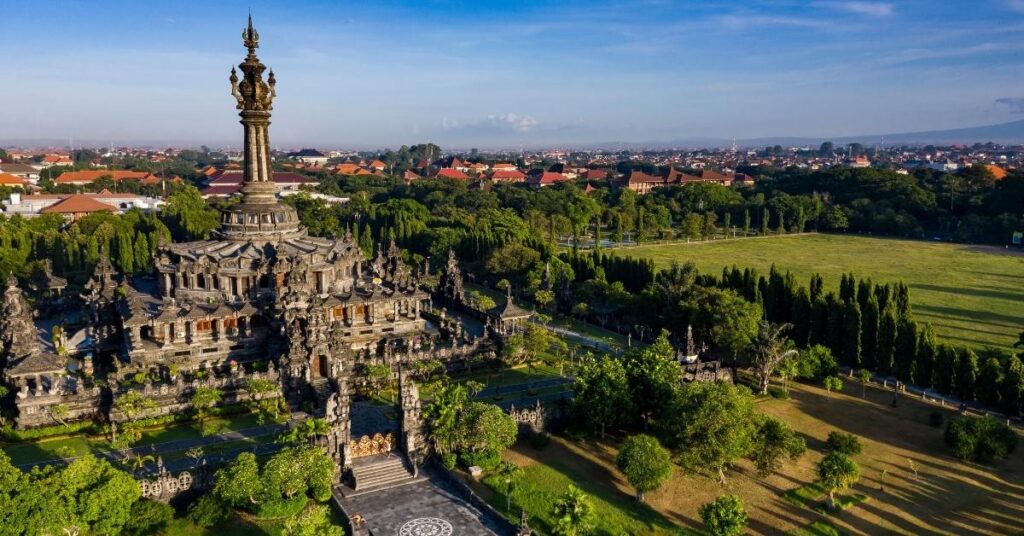 Aerial view of denpasar featuring bajra sandhi monument, green open space, and the city beyond.