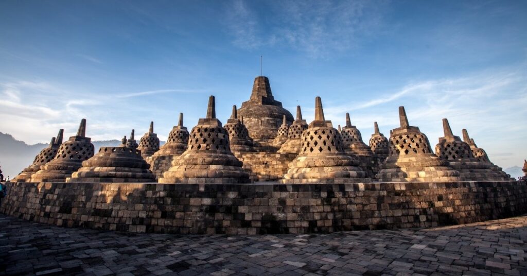 Borobudur temple in yogyakarta under a blue sky, showing its iconic stone stupas.