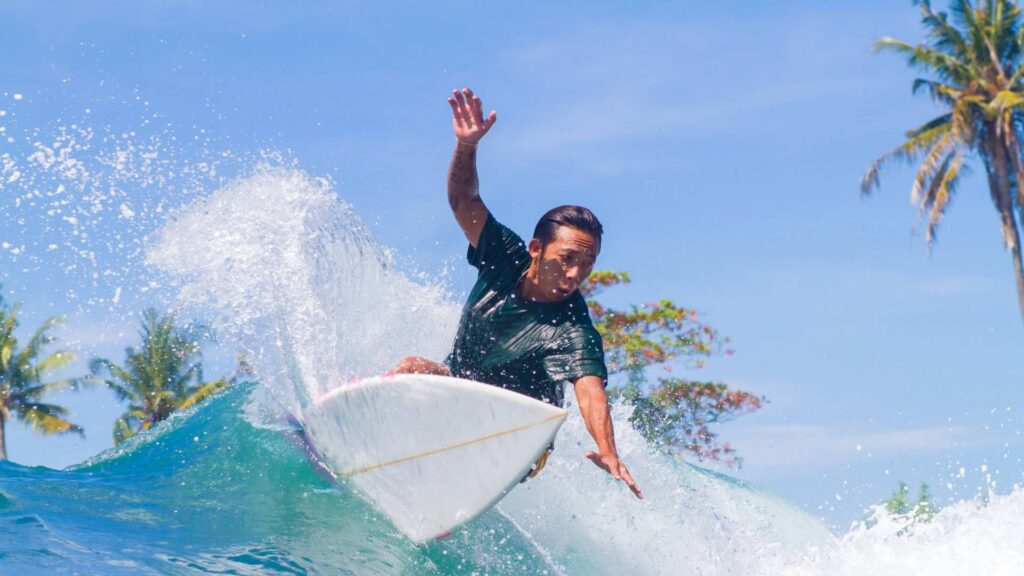 Surfer riding a tropical wave near palm trees, representing bali life for surfers