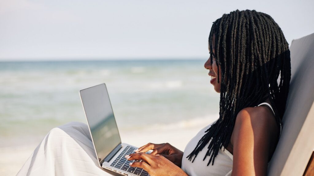 Remote worker using a laptop beside the beach while living and working in bali