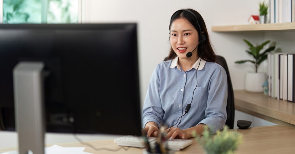 Customer service representative wearing a headset at a desk, symbolizing fast response support and telephone answering services from virtual office visa-indonesia.