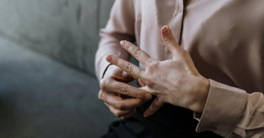 Крупним планом людина знімає обручку, що символізує розлучення і розлуку.