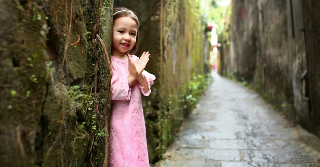 Молода дівчина посміхається у вузькому провулку, що символізує дітей та опікунство у справах про розлучення.