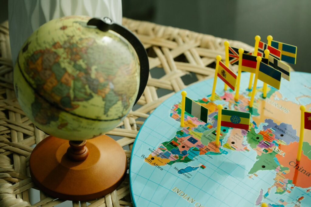 Un pequeño globo terráqueo y un mapa con las banderas de los países sujetas con alfileres, que muestran los países elegibles para las solicitudes de visado de turista c1 de indonesia.