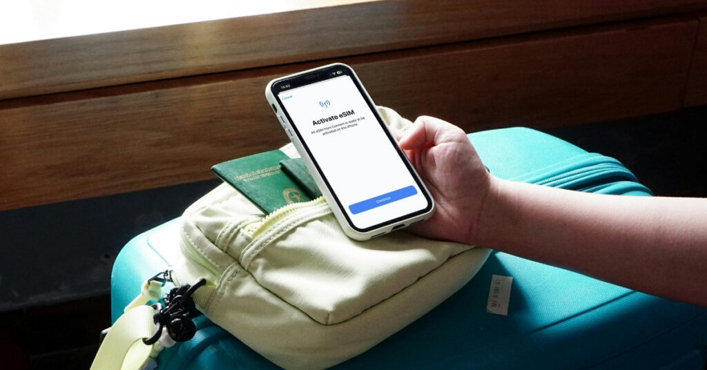 Phone showing an “activate esim” screen on top of luggage and passport. Setting up esim for bali before arrival.