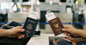 To reisende med amerikanske og thailandske pass og boardingkort ved innsjekkingsskranken på flyplassen, som velger mellom visum ved ankomst til Indonesia og fri innreise.