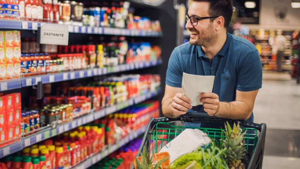 Man shopping for groceries in a supermarket, representing everyday food costs for australians living in bali.
