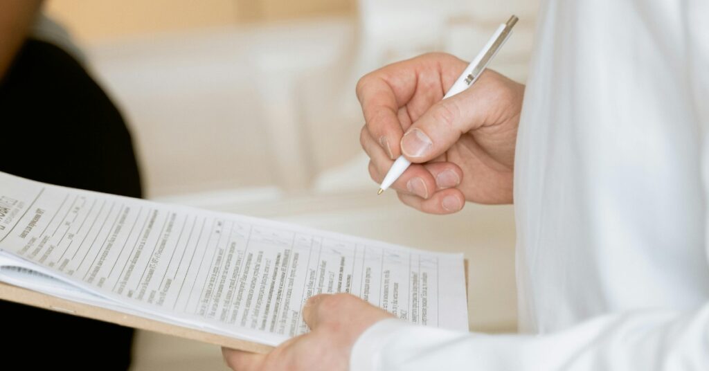 Zbliżenie na osobę wypełniającą dokumenty imigracyjne lub szpitalne, symbolizujące kroki prawne związane z rejestracją dziecka w Indonezji.