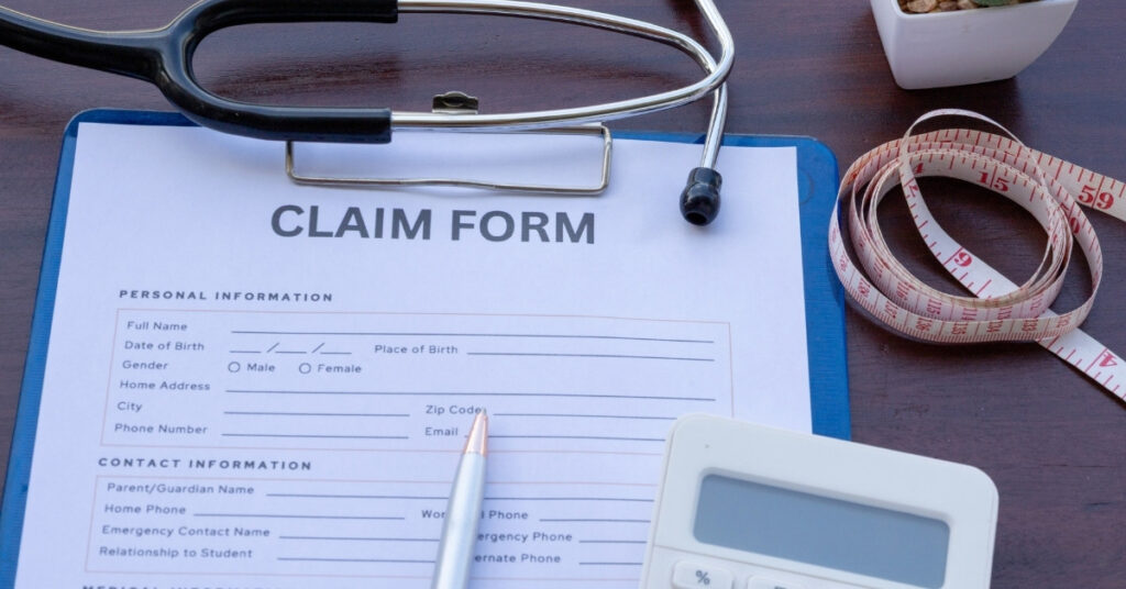 Бланк заявления на медицинское страхование на клипборде со стетоскопом, ручкой, калькулятором и рулеткой на столе