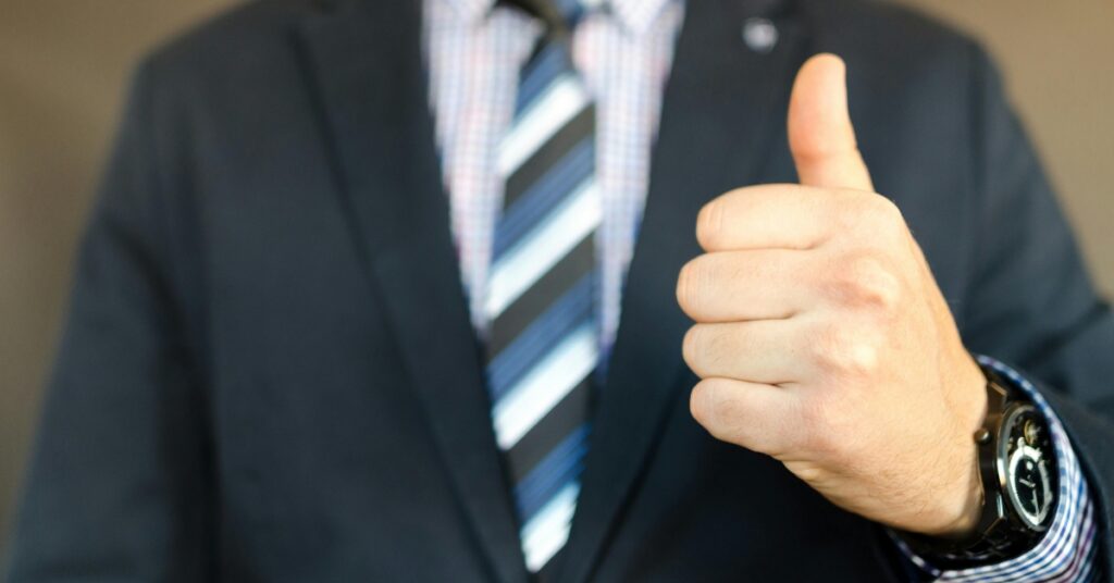 Бізнесмен у костюмі піднімає вгору великий палець, що символізує схвалення та успіх у процесі працевлаштування іноземних робітників в Індонезії.