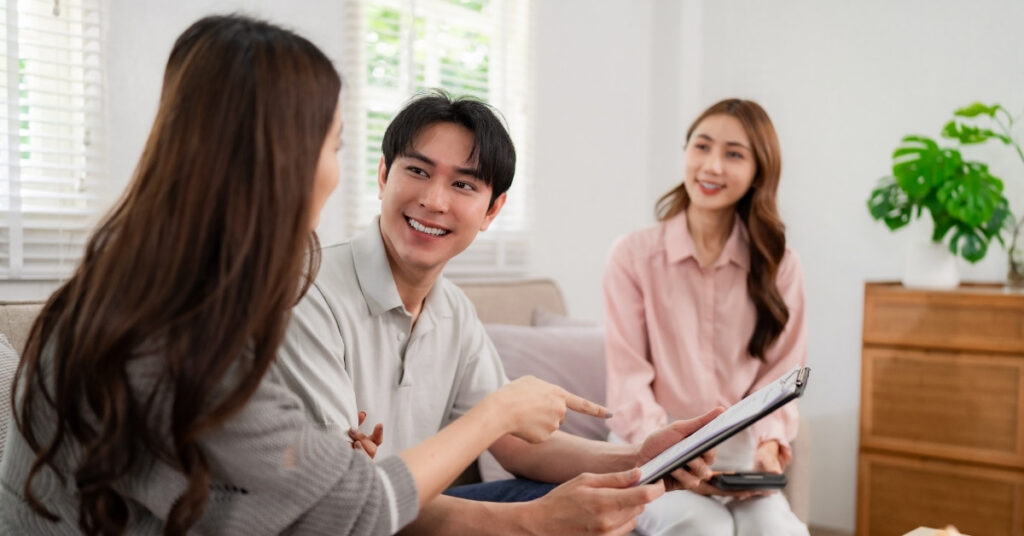 Foreign couple reviewing bpjs application documents with a consultant during a registration meeting in indonesia.