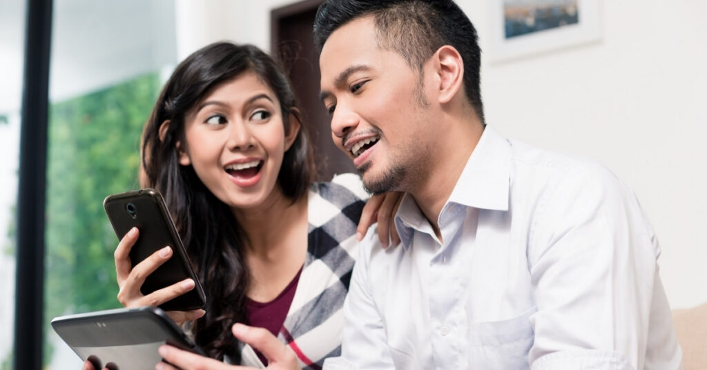 Former indonesian couple reviewing an ex-wni visa application on a phone and tablet, planning their return to indonesia.