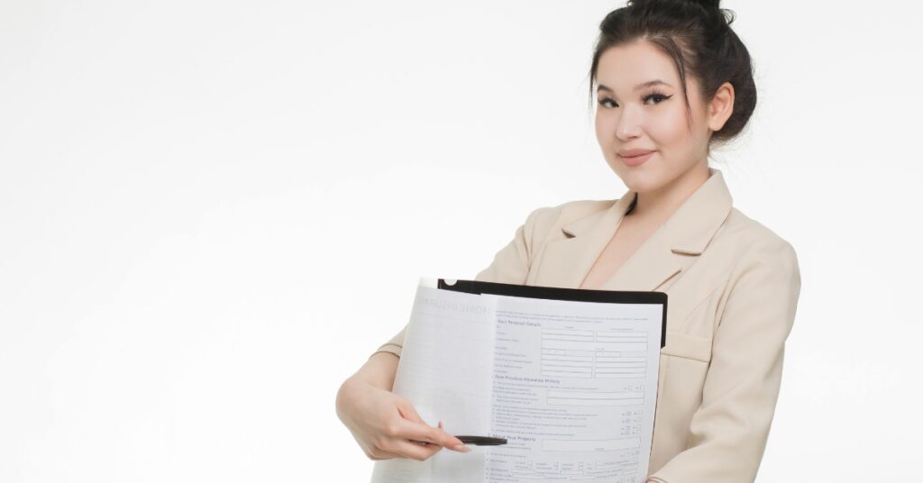A smiling young woman in a beige blazer presenting a travel insurance form, representing guidance on selecting the right policy.
