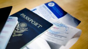 Primo piano di un passaporto posizionato su documenti di viaggio e carte su una scrivania, che illustra la fase di preparazione dei documenti per la mutazione dei passaporti in Indonesia.
