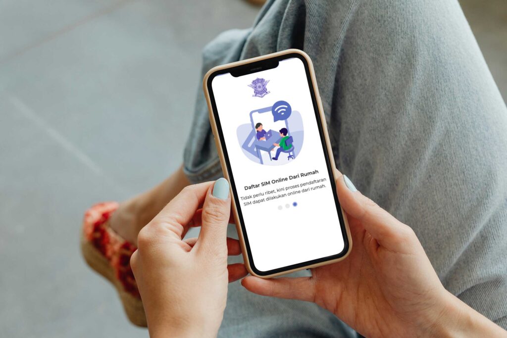 Een close-up van de handen van een vrouw die een smartphone vasthoudt waarop de Indonesische app voor online registratie van rijbewijzen (sim) te zien is. De interface van de app toont een digitale illustratie van mensen aan een bureau.