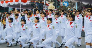 Національна прапорна команда Індонезії, паскібрака, марширує строєм під час офіційної церемонії святкування Дня незалежності у повній білій уніформі.