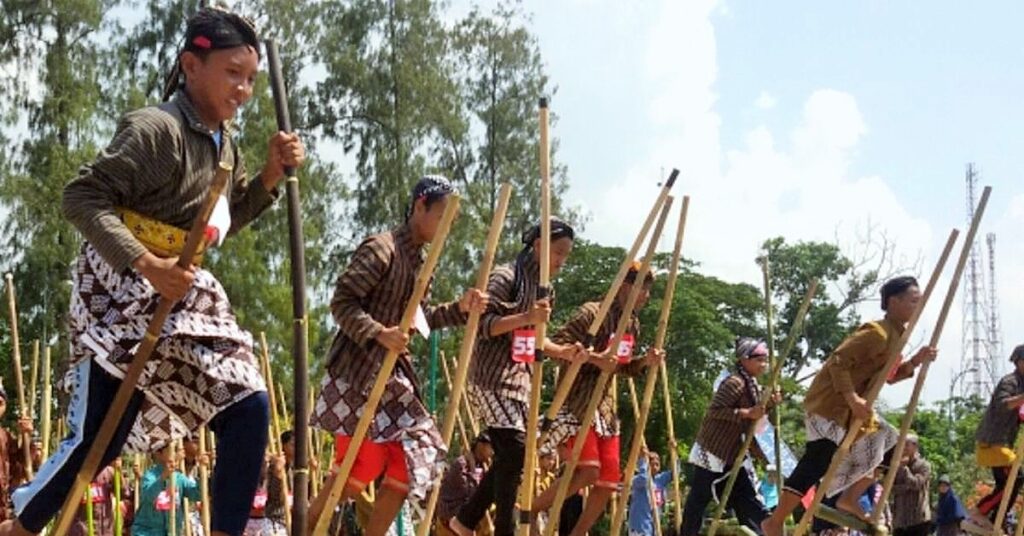Participantes con trajes tradicionales corren sobre zancos de bambú durante una competición festiva de Egrang para celebrar el Día de la Independencia de Indonesia.