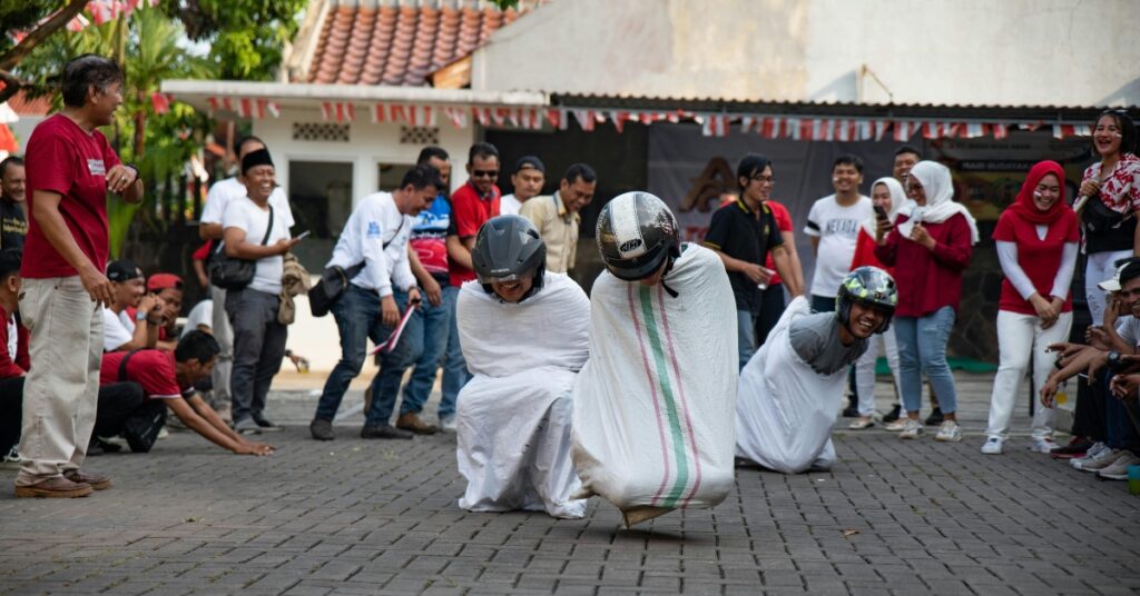Participantes con casco saltan en sacos mientras el público anima durante una divertida y animada competición de carreras de sacos por el Día de la Independencia de Indonesia.