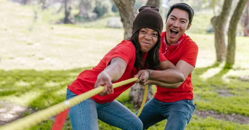 Dos personas con camisas rojas tiran con entusiasmo de una cuerda durante una competición de tira y afloja en un acto al aire libre por el Día de la Independencia en Indonesia.