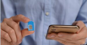 Elinde mavi bir sim ve telefon tutan, Endonezya sim kartı takan yolcunun yakın çekimi.