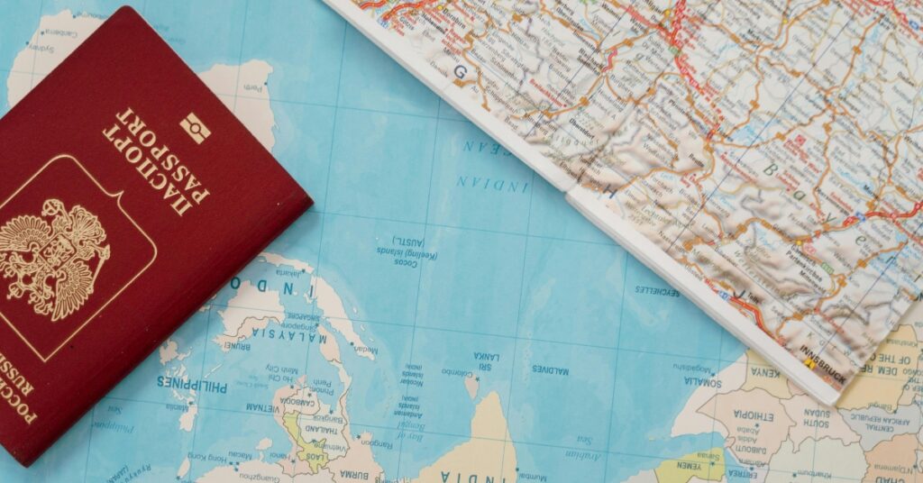 Rött internationellt pass på en karta över Asien och Stillahavsområdet med en hopvikt resekarta bredvid.