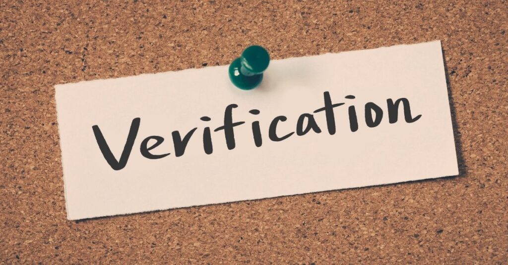 Paper note pinned to corkboard with the word verification, representing indonesia visa status stuck on waiting verification.