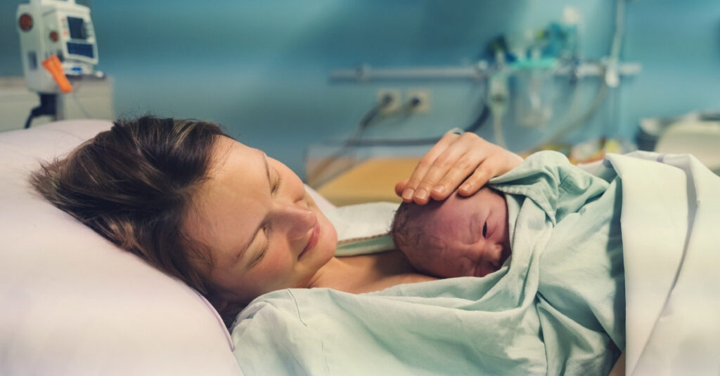 Mother holding her newborn skin-to-skin in a hospital room in indonesia right after delivery.