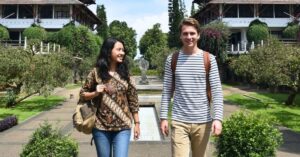 Indonesian and french student walking on a green campus during an indonesia student exchange program.