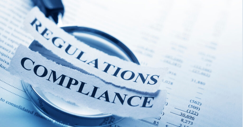 Magnifying glass over ‘Regulations’ and ‘Compliance’ legal rules you must meet to invest in Indonesia.