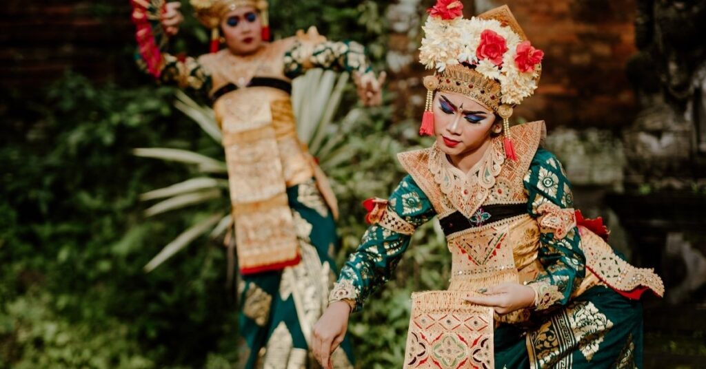 Danseurs balinais en costumes traditionnels colorés exécutant la danse kecak avec des mouvements expressifs.