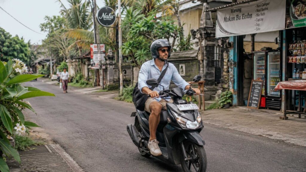 Buitenlandse professional pendelt per scooter door een lokale straat op Bali terwijl hij op het eiland woont en werkt.