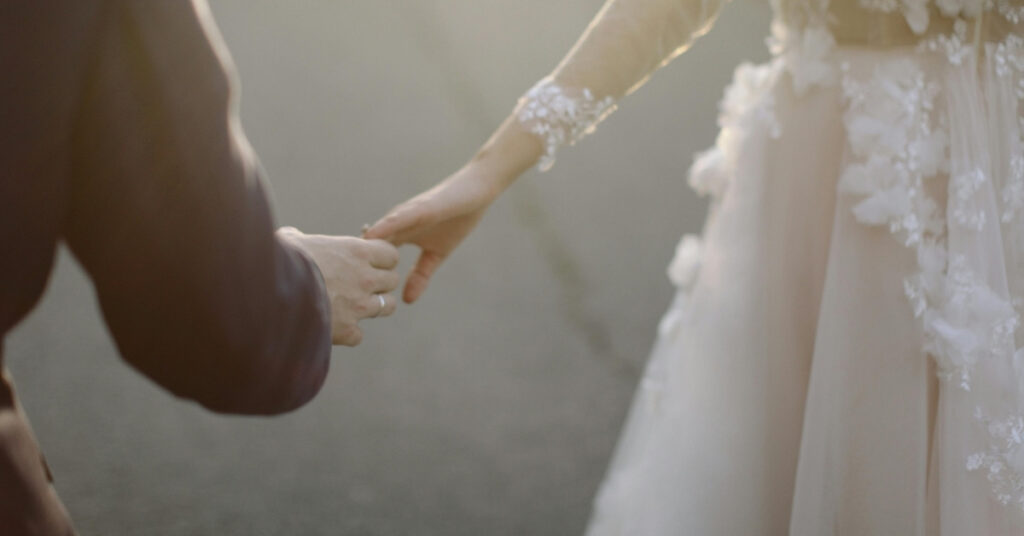 Наречений і наречена тримаються за руки у весільному вбранні, що символізує шлюб в Індонезії.