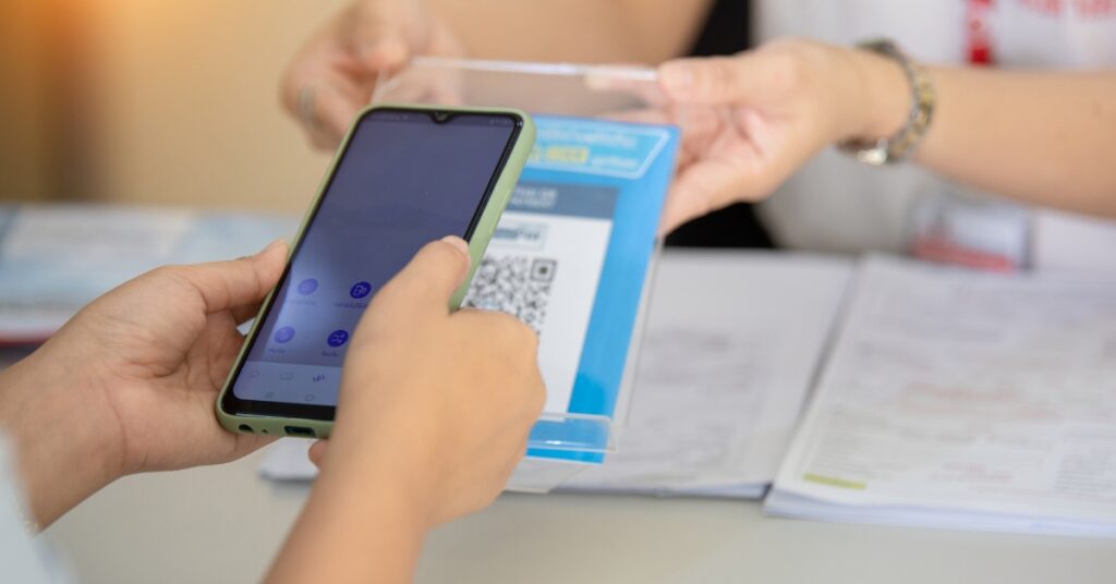 User holding a smartphone while scanning a qris code for a secure digital transaction.
