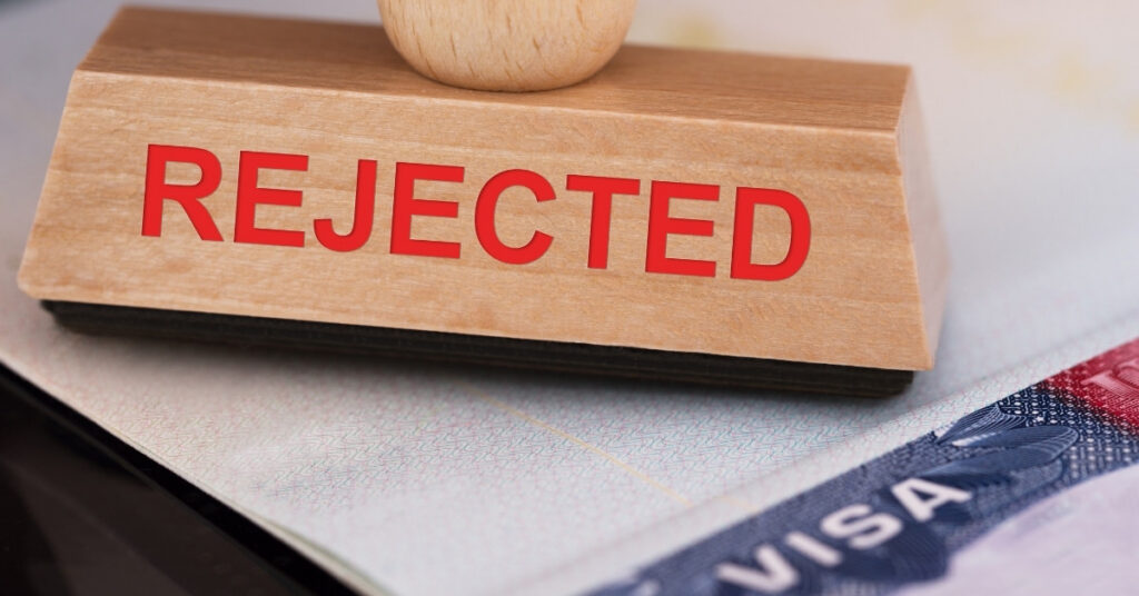 Wooden stamp with the word “rejected” placed on a passport and visa page, illustrating an indonesian visa rejection.