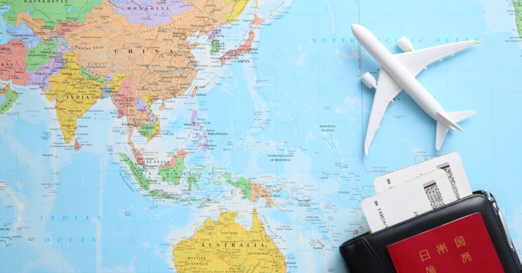 Et kort over Asien og Australien med et pas, boardingkort og et legetøjsfly, der repræsenterer kravene til at blive indonesisk statsborger.