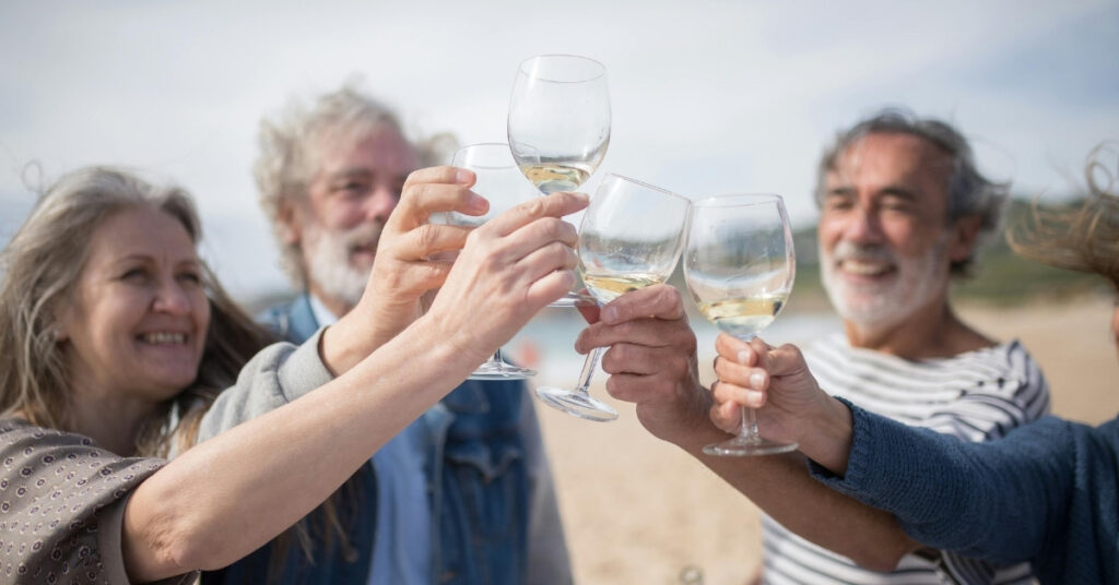 Група пенсіонерів святкує разом на пляжі в Балі з келихами вина.