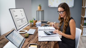 Female accountant reviewing invoices and calculating pt pma tax documents in a modern office.
