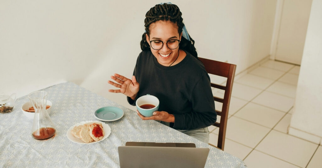 Remote worker on a video call at home with a laptop and tea, showing a business run remotely without physical office space.
