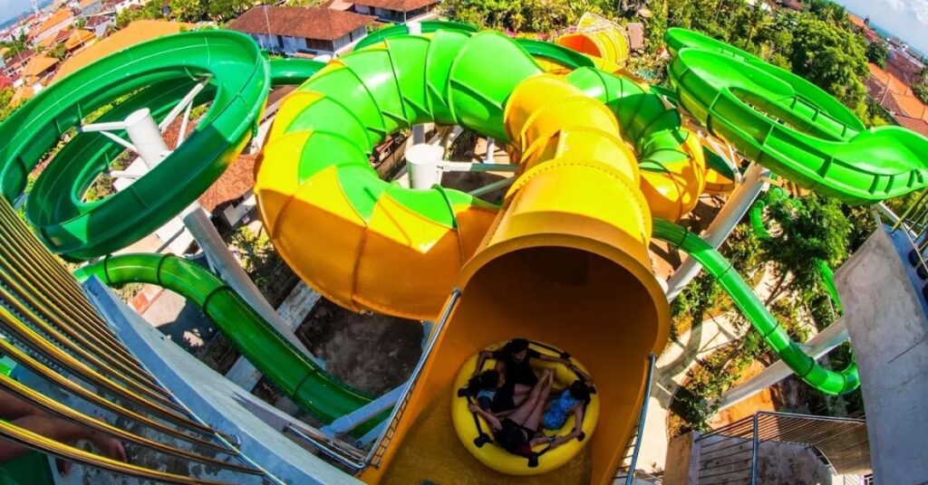 Un groupe profite d'un toboggan aquatique jaune vif et vert à Waterbom Bali, l'un des meilleurs parcs aquatiques familiaux d'Asie.