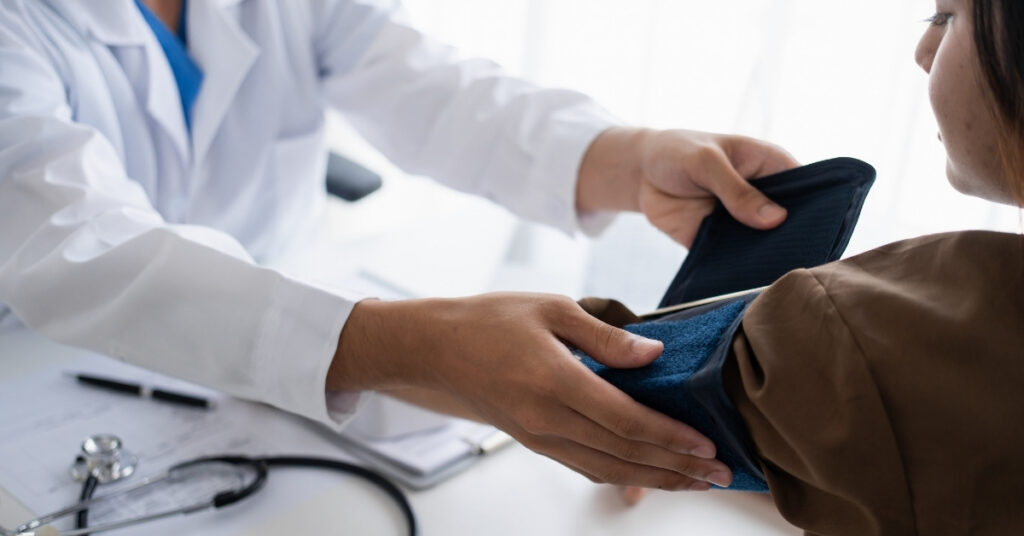 Doctor checking a patient’s blood pressure during a medical exam, representing bpjs-covered healthcare services in indonesia.