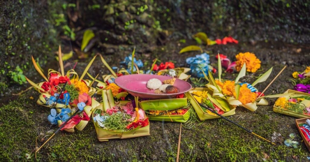 Balinesiske offergaver (canang sari) med blomster, røkelse og mat som legges på bakken under forberedelsene til nyepi-ritualet.