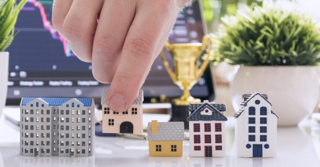 Hand choosing miniature buildings with market chart, picking locations and sectors to invest in Indonesia.